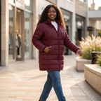 HHE plus size women's packable puffer coat in burgundy red, warm and comfortable everyday wear, model walking on a city street.